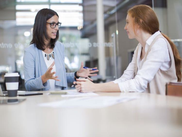 Life coach sits with a client in conference room with glass walls
