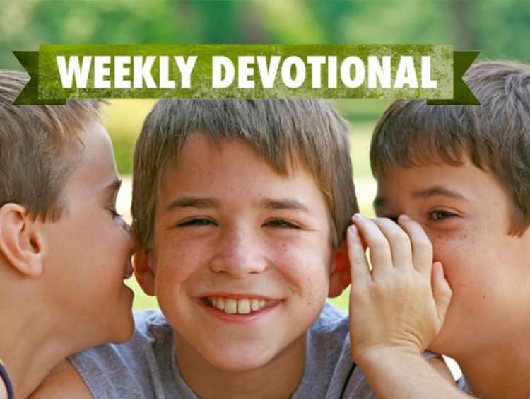 Students whispering to each other under the weekly devotional banner