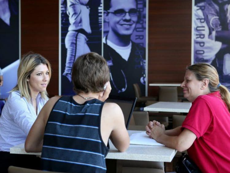 three people sitting around a table and talking