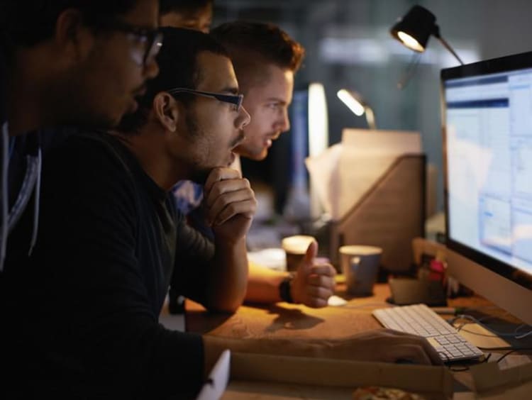 three men looking at a computer