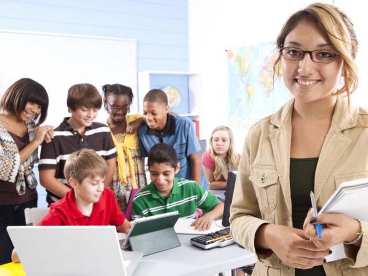 teacher smiling and students working in the background