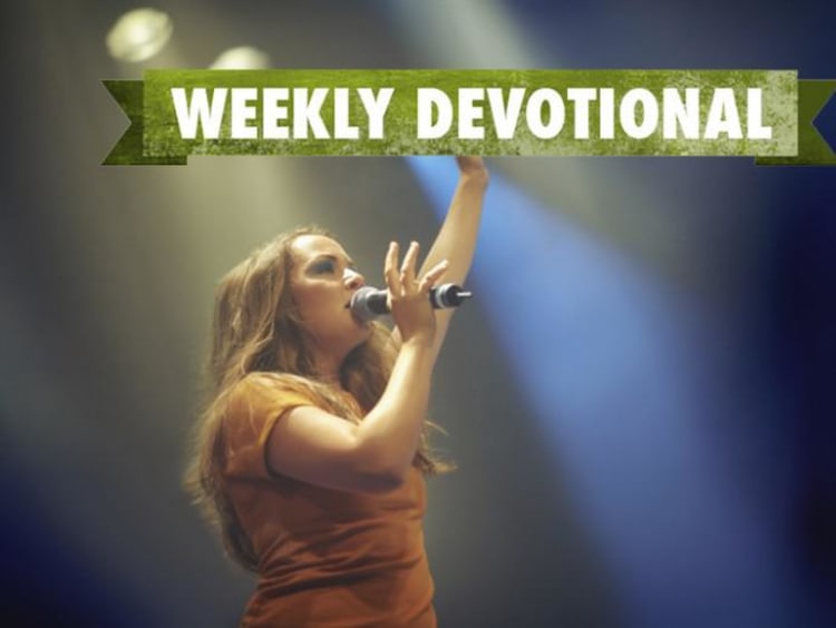 A woman singing under the Weekly Devotional banner
