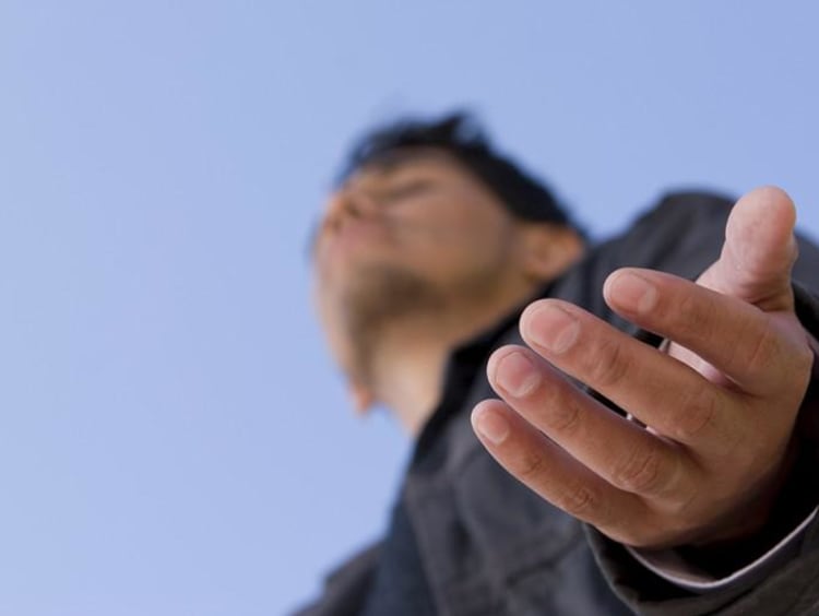 Man holds his hands out with eyes closed to receive God's Blessing