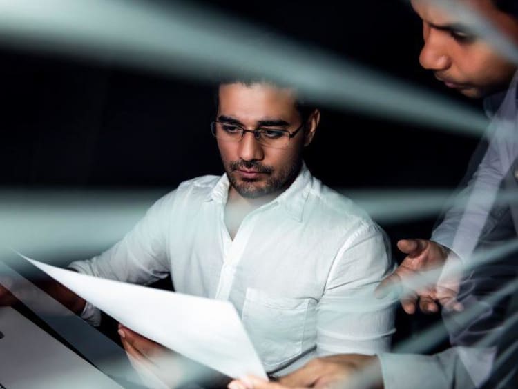 man showing another man a piece of paper