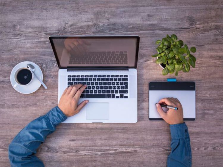 typing on computer with coffee