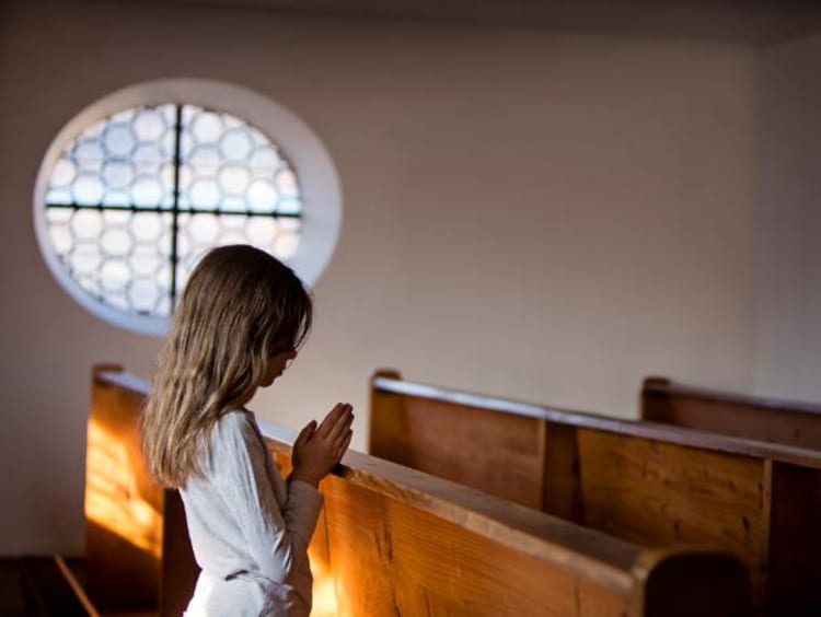 Little girl praying on pew