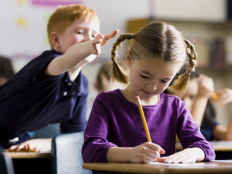 Little boy about to pull little girl's braid in class