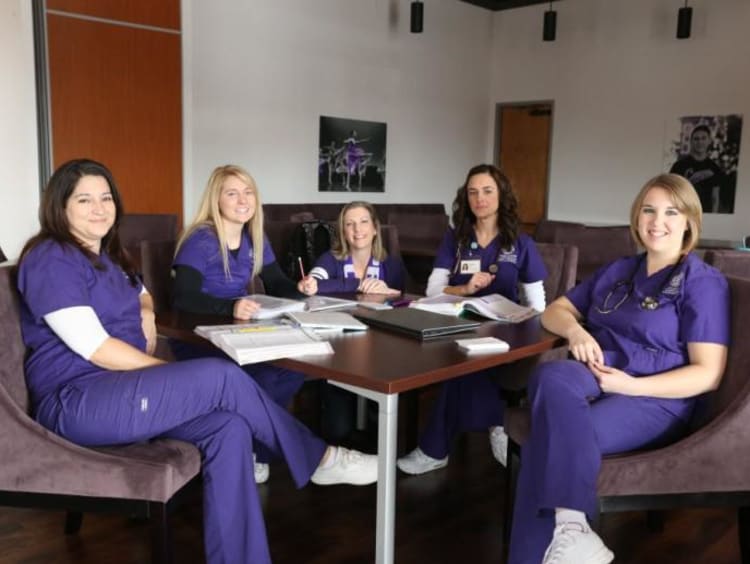 five nurses sitting around a table working