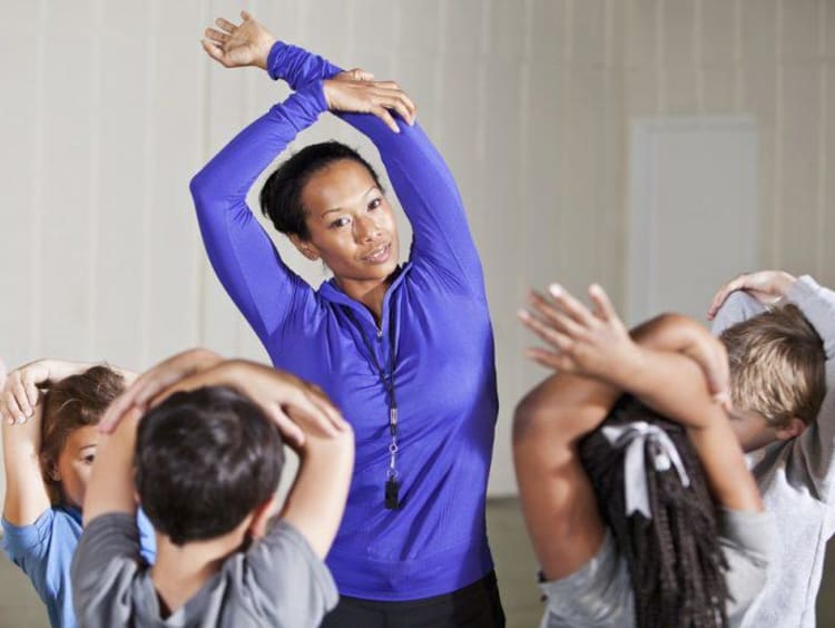PE teacher stretches with students