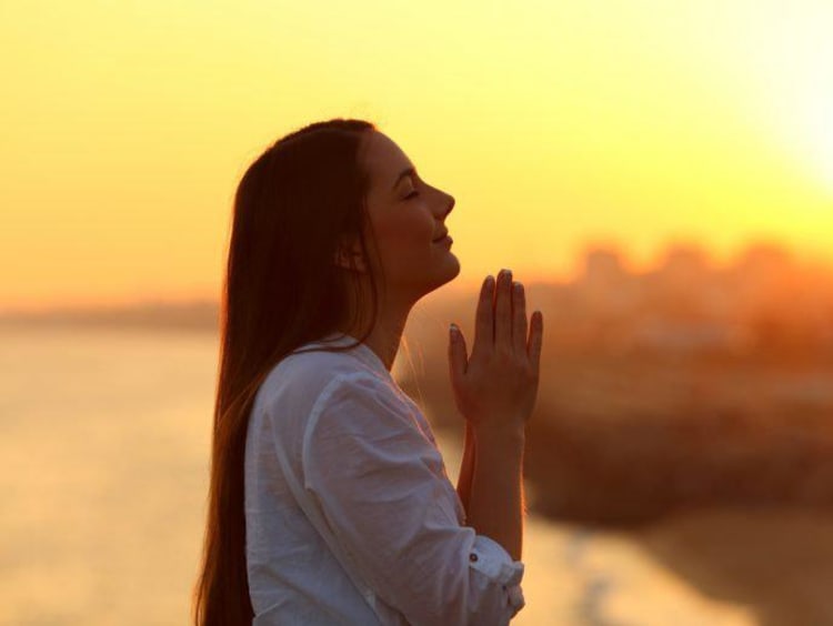 woman praying during sunrise or sunset