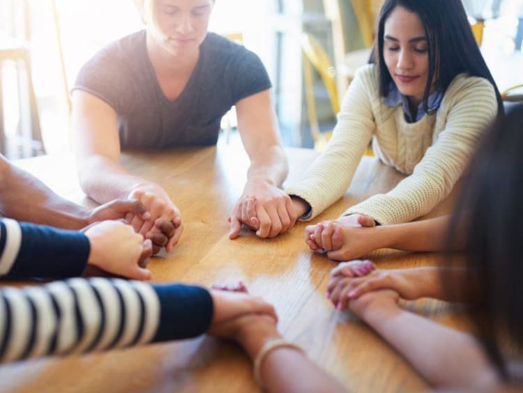 Group holding their hands together in prayer
