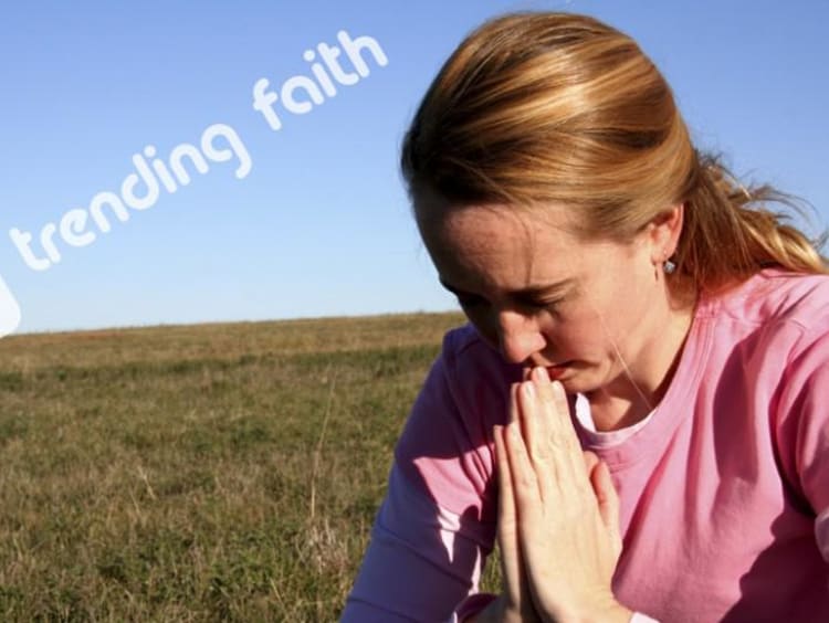A woman praying in a field under the Trending Faith logo
