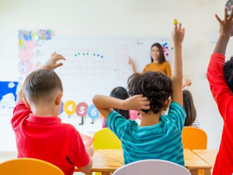 Elementary students raising their hands