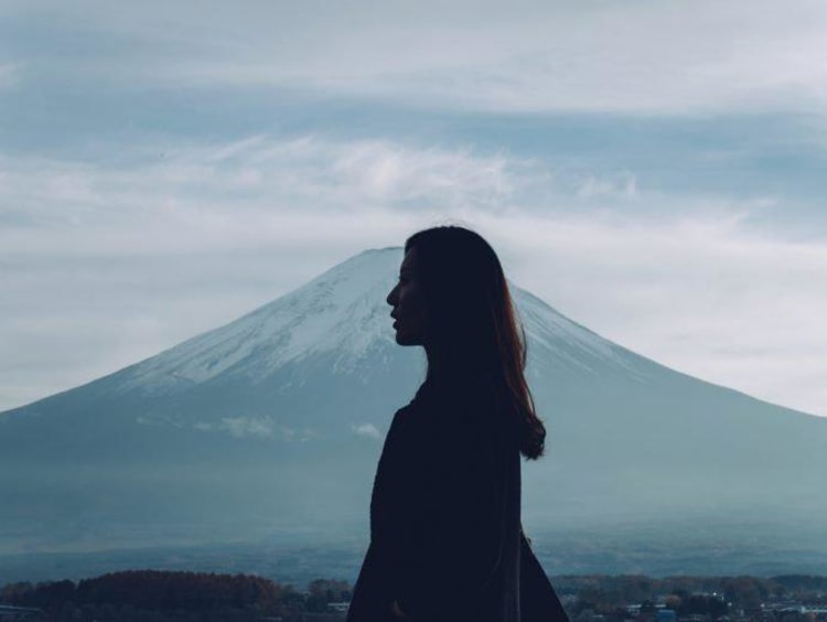 A girl looking out into the distance with a mountain behind her