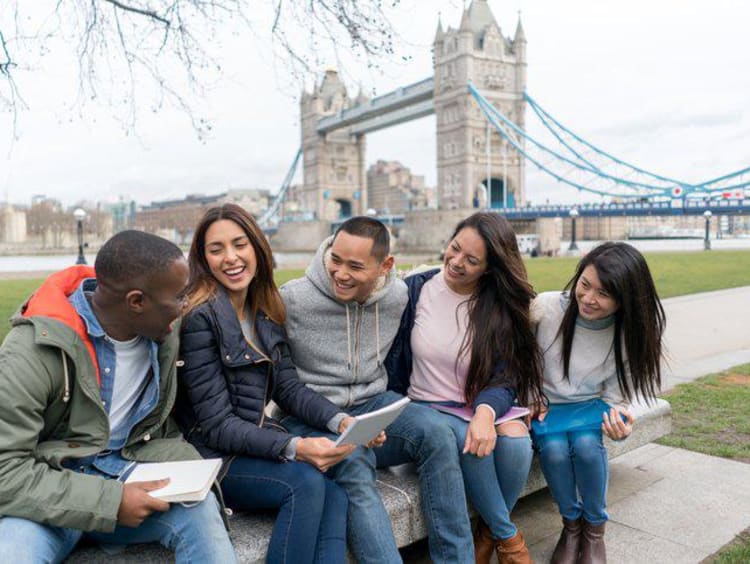 group of students sitting on bench in front of Tower Bridge in London