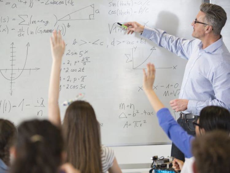 Male teacher leading physics lesson at whiteboard in classroom