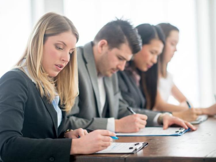 four people sitting at a table signing paperwork