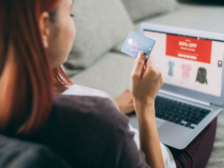 Woman shopping online with card in hand