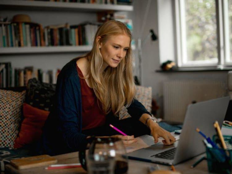 Blonde female student takes notes from online counseling class