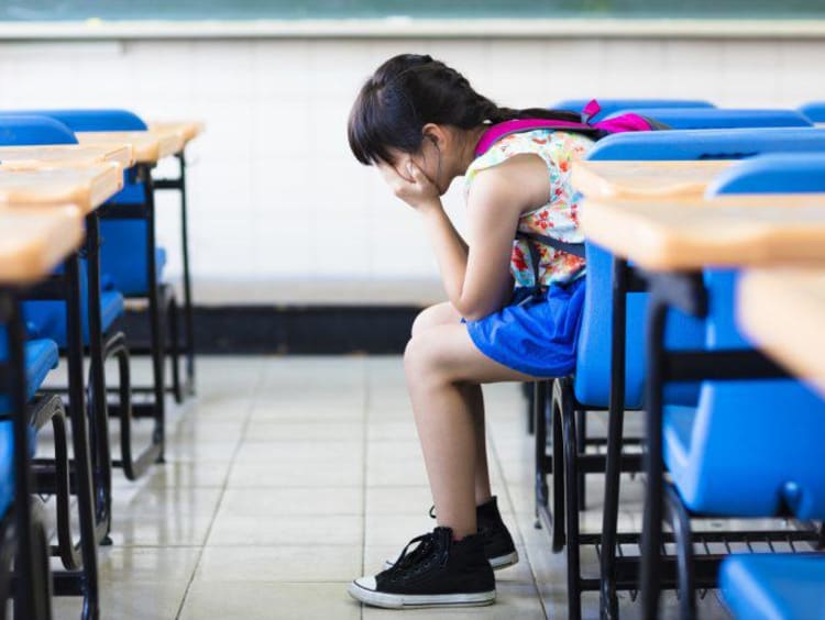 kid sitting in a classroom with head in hands