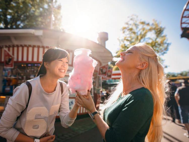 two girls at a carnival eating cotton candy