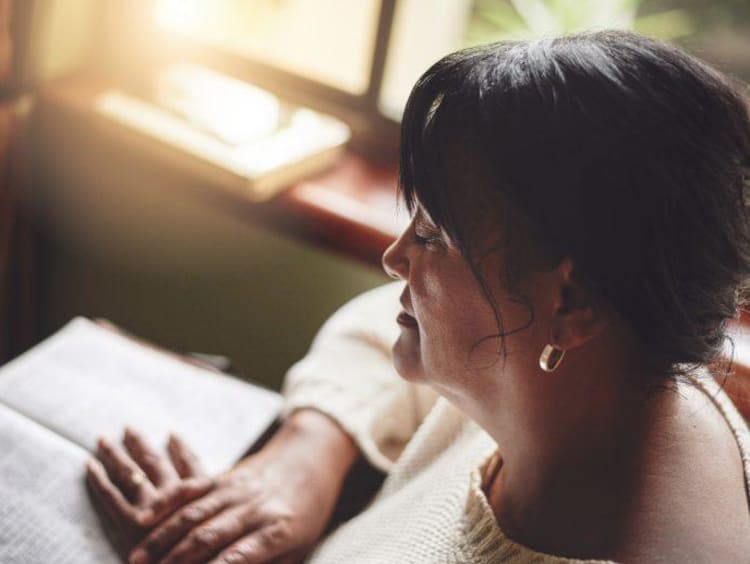 a woman praying over her Bible