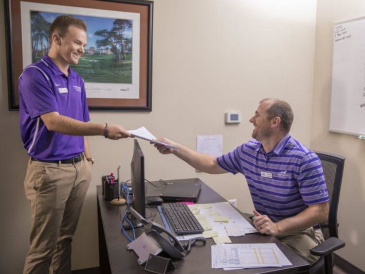 Two GCU golfers interacting in an office