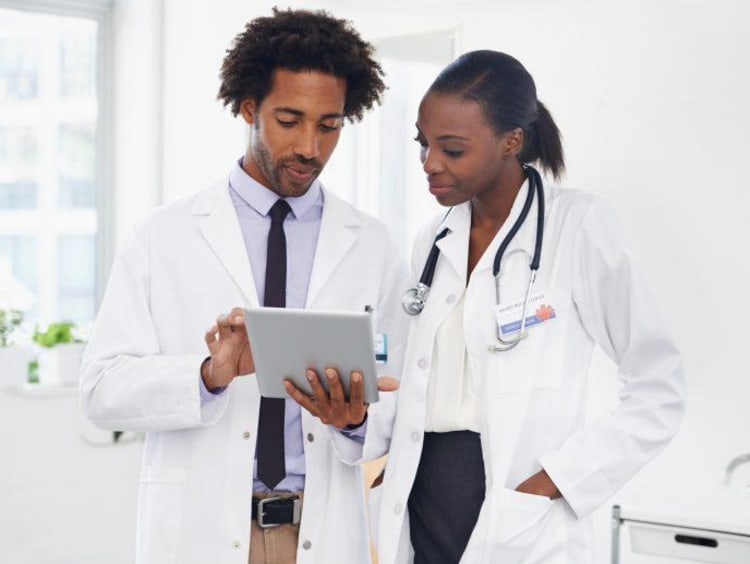 Two African-American doctors review results on tablet