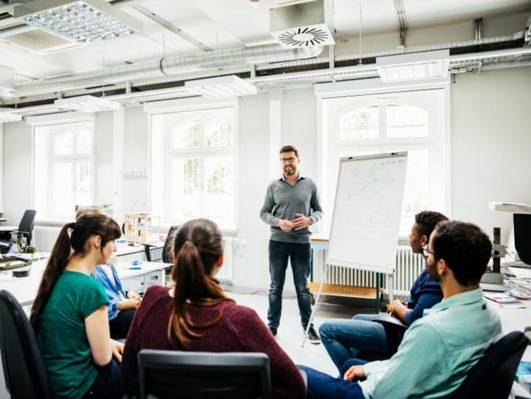 University Tutor Speaking To Students During Seminar