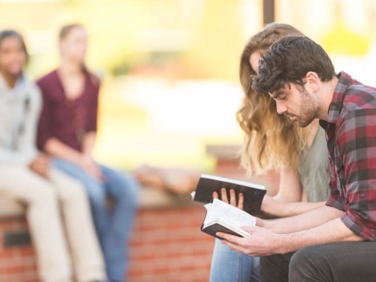 two people reading a book outside