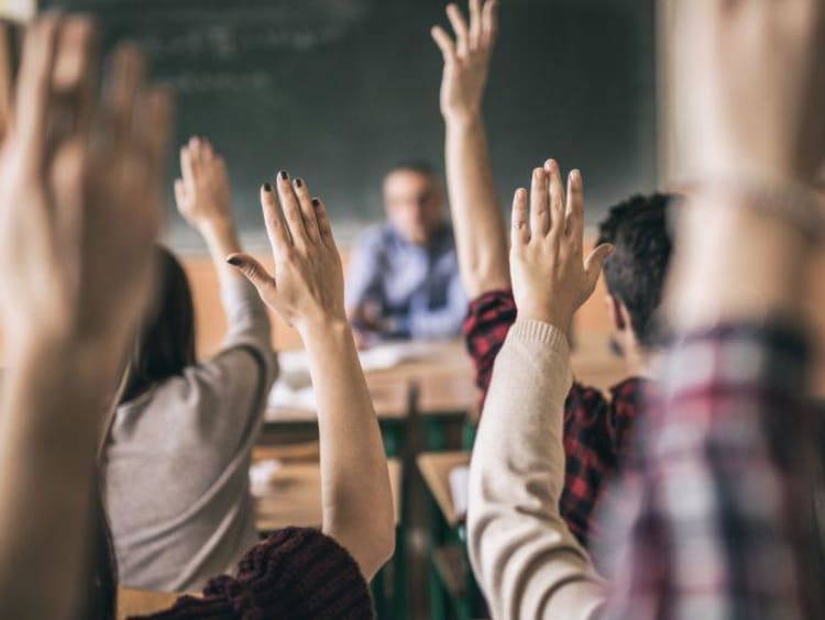 students raising their hand in the classroom