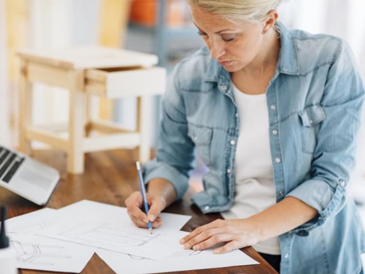 Middle-aged woman works on a table sketch design
