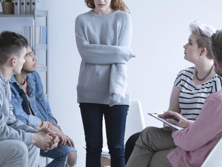 Girl holding her arm in a group counseling setting