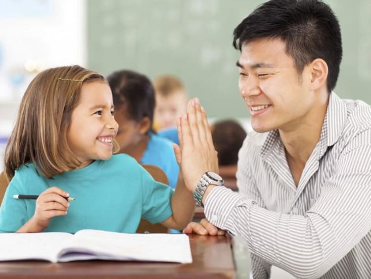 Male teacher gives younger female student a high five