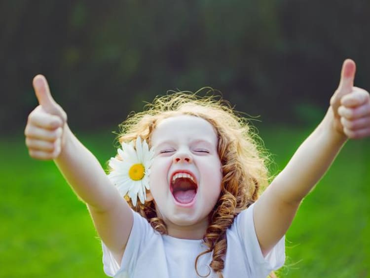 Girl in a field holding two thumbs up