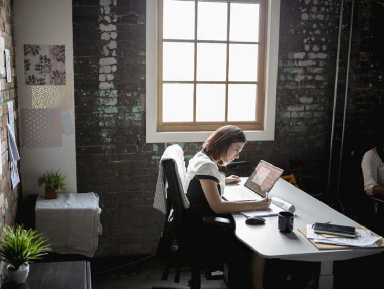 Woman sitting at desk in office next to window