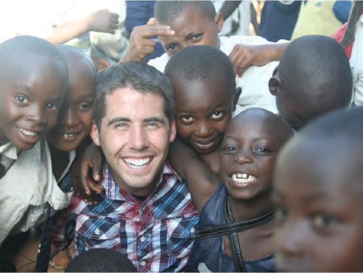 A man surrounded by a group of happy children