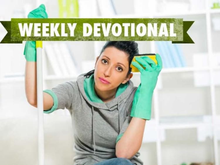 Woman wearing cleaning gloves looks tired with sponge in hand