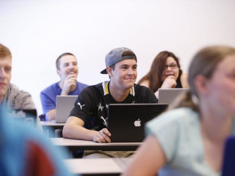 College students smile while facing ahead towards the professor
