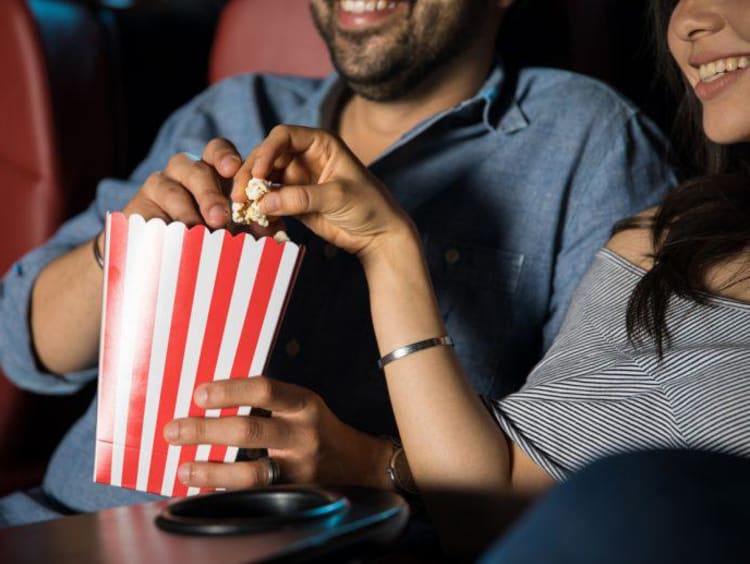 two people eating popcorn at the movies