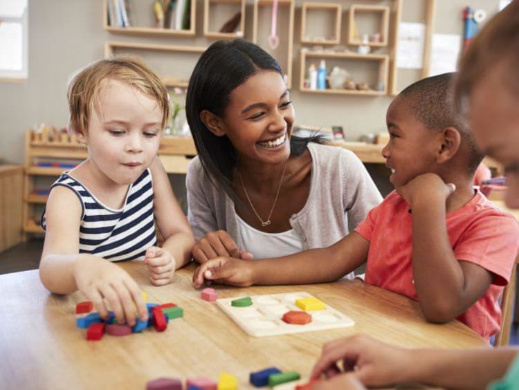 Teacher smiling helping little kids