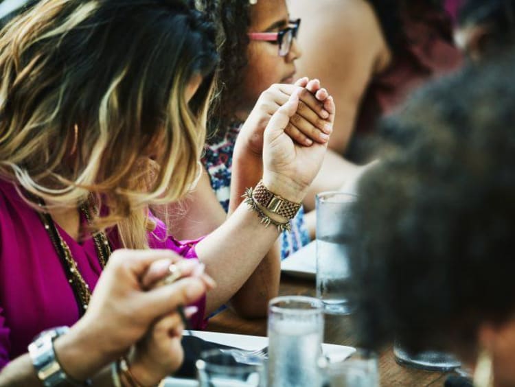 people holding hands at a table