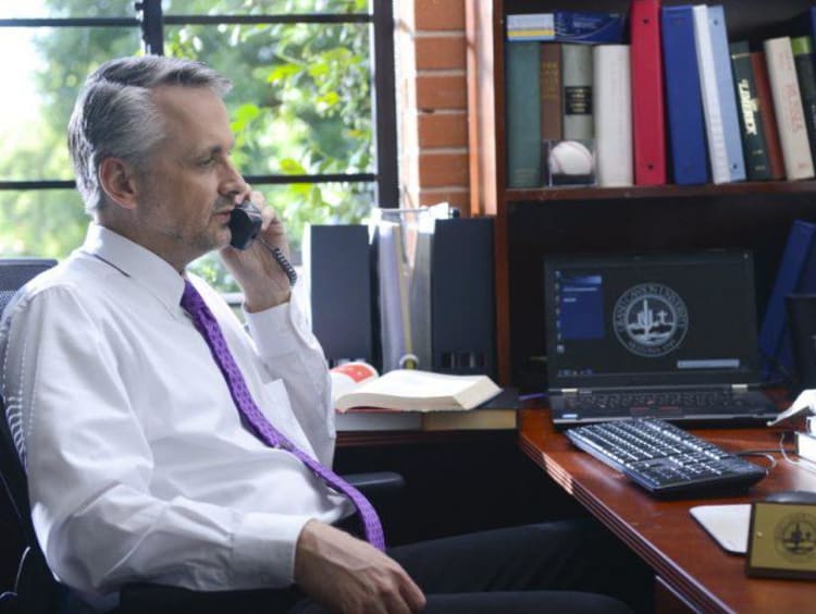 Doctoral education leader speaks on the phone in his office