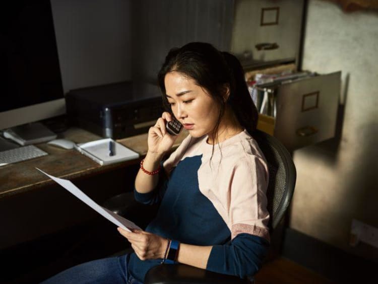 woman on the phone and reading off a paper