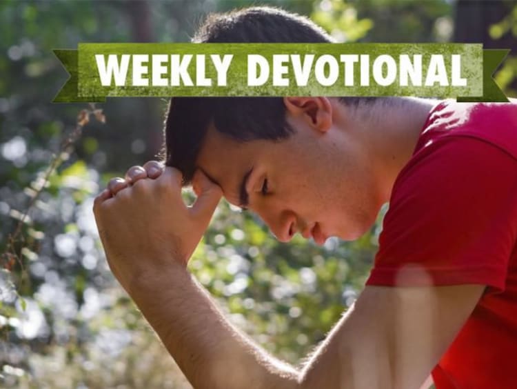 A man with his head bowed under the Weekly Devotional banner