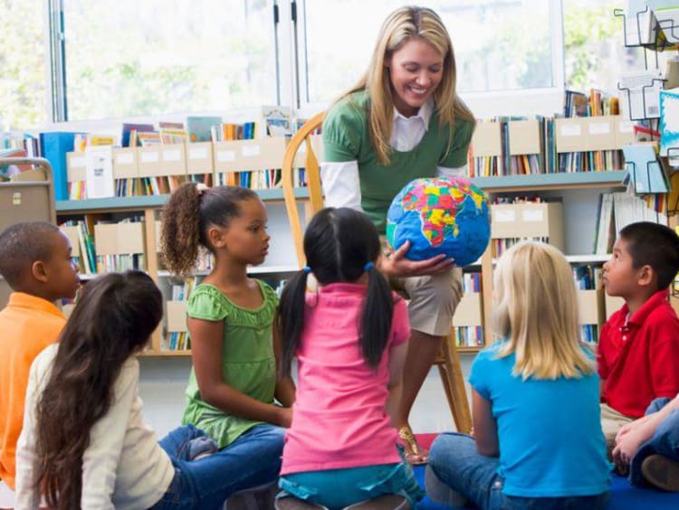 teacher showing a globe to young students