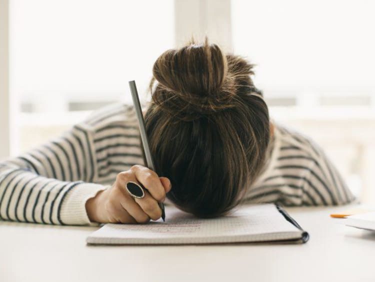 Overwhelmed student with her head on her desk