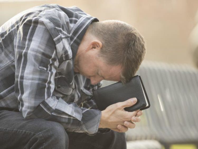 man with head down praying