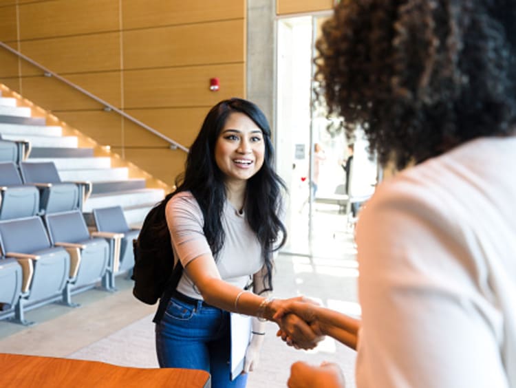 female student and teacher shaking hands when talking during office hours