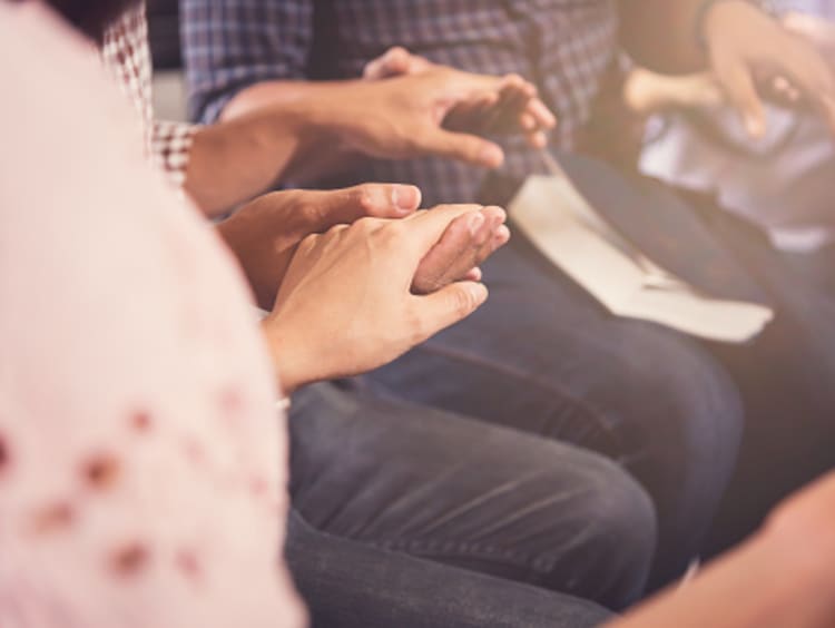 Christians encouraging one another by holding hands and praying